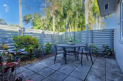 a patio with a table and chairs and a fence at Wilton Manors Twin Oasis | 2 Heated Pools, For 12 in Fort Lauderdale