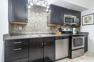 a kitchen with black cabinets and a sink and a microwave at Wilton Manors 2BR Bungalow, Private Pool, Sleeps 6 in Fort Lauderdale