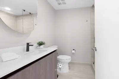a bathroom with a sink and a toilet and a mirror at Chic 2BR Apartment Gym & Balcony Views in Miami Beach