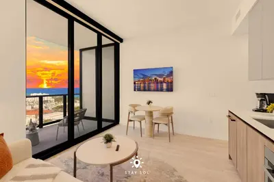 a kitchen and living room with a table and chairs at Coastal Apartment - Pool & Breezy Balcony in Miami Beach