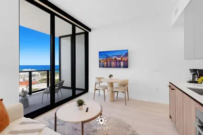 a kitchen and living room with a table and chairs at Coastal Apartment - Pool & Breezy Balcony in Miami Beach