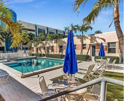 a table with blue umbrellas and chairs next to a swimming pool at Exclusive studio steps to the beach with pool in Hollywood