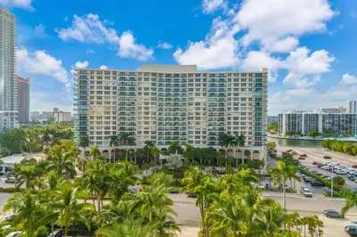 a tall building in a city with palm trees at Family-Friendly Beach Condo Steps to the Ocean- 9th floor in Hollywood Beach