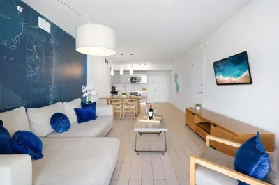 a living room with a white couch and blue pillows at Amazing 2 BR Apartment Pool & Near Beach in Hallandale Beach