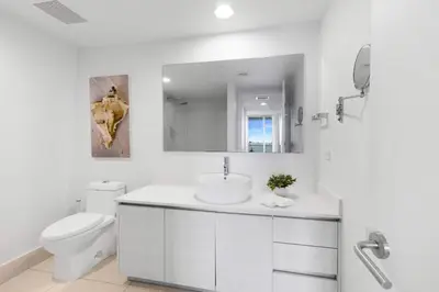 a white bathroom with a toilet and a sink at Amazing 2 BR Apartment Pool & Near Beach in Hallandale Beach