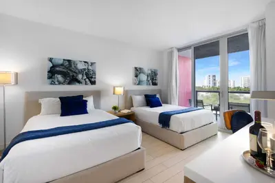 a hotel room with two beds and a window at Amazing 2 BR Apartment Pool & Near Beach in Hallandale Beach
