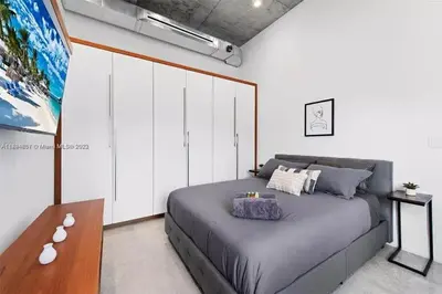 a bedroom with a gray bed and a table at Villa Retro Mirage in Biscayne Park