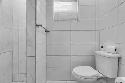 a white bathroom with a toilet and a shower at Tropical Haven Cozy 1 BR Caribbean Getaway in Miami