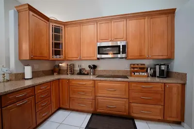 a kitchen with wooden cabinets and a microwave at Poolside Miami Paradise with BBQ & Outdoor Lounge in Miami