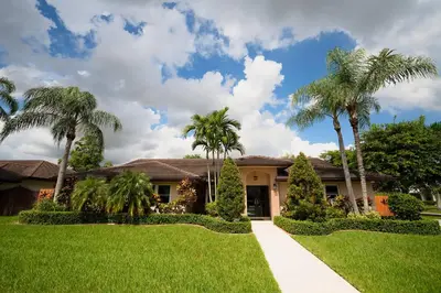 a house with palm trees in front of a yard at Poolside Miami Paradise with BBQ & Outdoor Lounge in Miami
