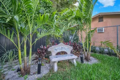 a bench in a yard with trees and a fence at Buena Vista Oasis - 3BR Home Near Art District Family in Miami