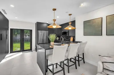 a kitchen with a black counter and white chairs at Buena Vista Oasis - 3BR Home Near Art District Family in Miami