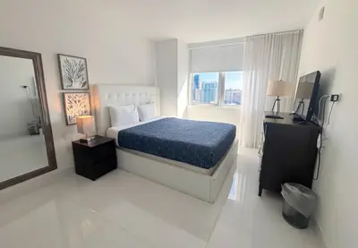 a bedroom with a bed and a mirror and a television at Luxury Ocean View Penthouse 2501 Hallandale Beach in Hallandale Beach