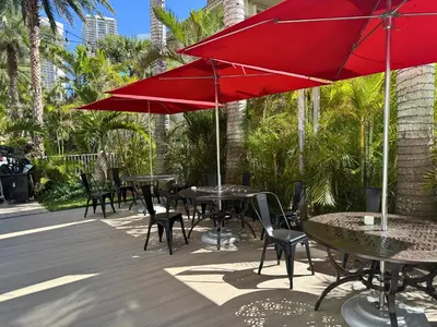 a group of tables and chairs with red umbrellas at Luxury Ocean View Penthouse 2501 Hallandale Beach in Hallandale Beach