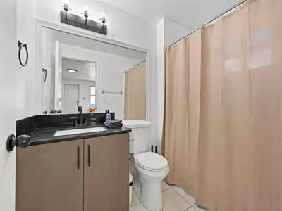 a bathroom with a toilet and a sink and a mirror at Studio Sol Little Havana Retreat in Miami
