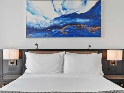 a bedroom with a white bed with a painting above it at Villa Seafoam in Miami Beach