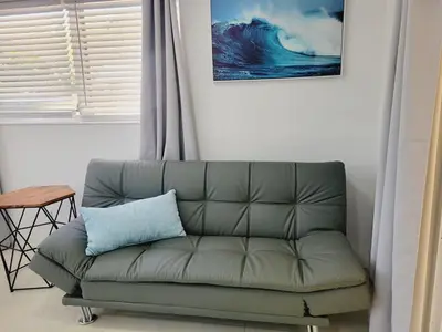 a couch with a blue pillow sitting in a living room at Kevin#B Chic Studio with Patio near Fort Lauderdale Beach in Fort Lauderdale