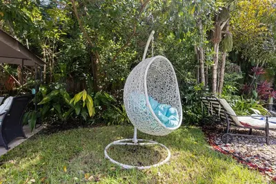 a metal chair in the grass in a garden at 3-Bedroom Villa with Heated Pool near Wilton Drive & Fort Lauderdale Beach in Fort Lauderdale