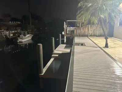 a dock with a palm tree and a boat on the water at Riverfront- Home in Hollywood