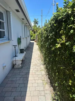 a sidewalk next to a white house with a hedge at The Hollywood Beach Experience in Hollywood