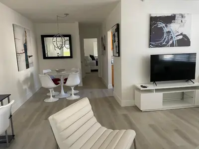 a living room with a television and a table and chairs at Beach Escape in Fort Lauderdale