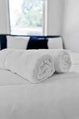a stack of white towels sitting on a bed at Modern 2-Bedroom Apartment in Miami