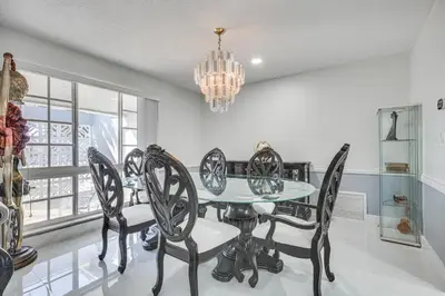 a dining room with a glass table and chairs at 3 Mi to Hard Rock Stadium Home with Fenced-In Yard! in Miramar