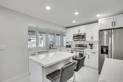 a kitchen with white cabinets and a large kitchen island at 3 Mi to Hard Rock Stadium Home with Fenced-In Yard! in Miramar