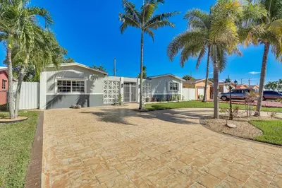 a driveway with palm trees in front of a house at 3 Mi to Hard Rock Stadium Home with Fenced-In Yard! in Miramar