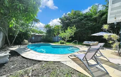 a small swimming pool with two chairs and an umbrella at The Perfect South Florida Experience in Fort Lauderdale