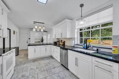 a kitchen with white cabinets and black counter tops at Stunning Tropical Getaway Steps To The Beach with Pool in Hollywood