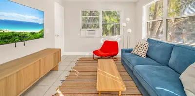 a living room with a blue couch and a red chair at The Jute Box - Pool - Waterview - Wilton Drive in Fort Lauderdale