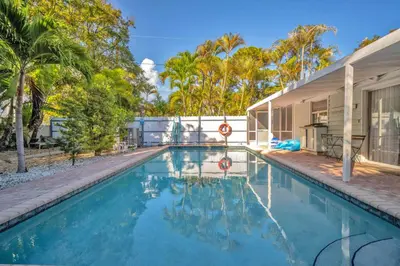 a swimming pool in front of a house with trees at The Jute Box - Pool - Waterview - Wilton Drive in Fort Lauderdale