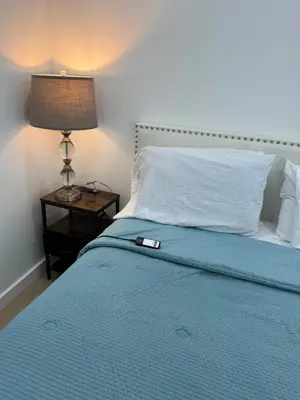 a bed with a blue blanket and a lamp on a table at Comfy and Relaxed in Cutler Bay
