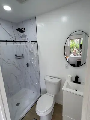 a bathroom with a toilet and a shower and a mirror at Comfy and Relaxed in Cutler Bay