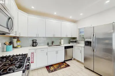 a kitchen with white cabinets and a stainless steel refrigerator at The Front House in Fort Lauderdale