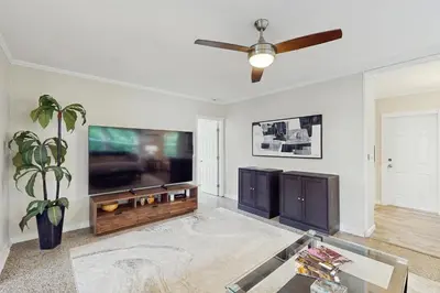 a living room with a flat screen tv and a ceiling fan at The Cottage in Fort Lauderdale
