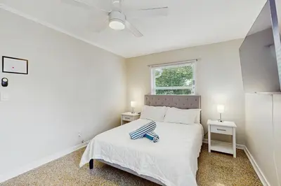 a white bedroom with a bed and a window at The Cottage in Fort Lauderdale