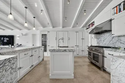 a white kitchen with marble counter tops and appliances at Isla Solana by Rove Travel - Waterfront with Pool in Miami