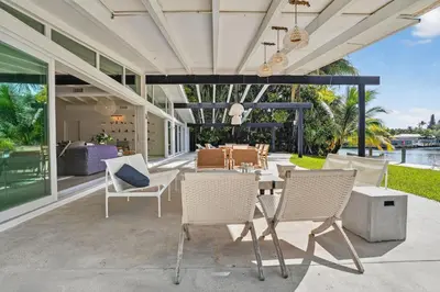 a patio with white chairs and a table with a dining room at Isla Solana by Rove Travel - Waterfront with Pool in Miami