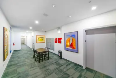 a hallway with a table and chairs and paintings at Wynwood Retreat - Rooftop Pool & Neighborhood Views in Miami