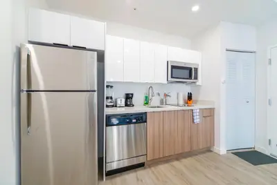 a kitchen with white cabinets and a refrigerator at Wynwood Retreat - Rooftop Pool & Neighborhood Views in Miami