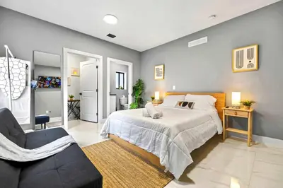 a bedroom with a large bed and a chair at Central Miami Studio - Wynwood 8 Min in Miami