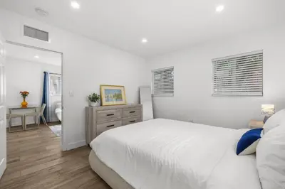 a white bedroom with a bed and a mirror at Cozy By The Blue in Miami