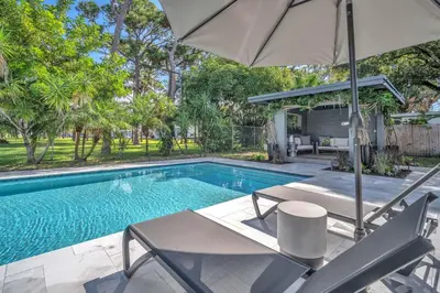 a swimming pool with an umbrella and two chairs and a table at Almost Famous - Pool - Jacuzzi in Fort Lauderdale