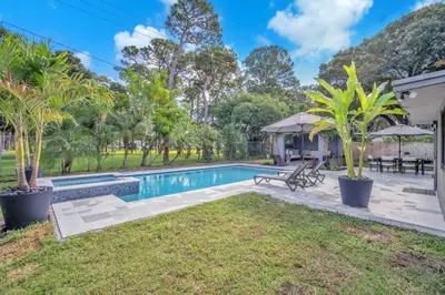 a swimming pool in a yard with palm trees at Almost Famous - Pool - Jacuzzi in Fort Lauderdale