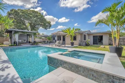 a swimming pool in the backyard of a home with palm trees at Almost Famous - Pool - Jacuzzi in Fort Lauderdale