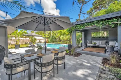 an outdoor patio with an umbrella and a pool at Almost Famous - Pool - Jacuzzi in Fort Lauderdale