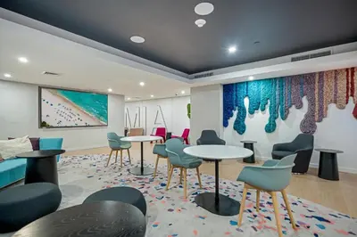 a waiting room with tables and chairs and a painting at Skyline Studio Workspace & Rooftop Pool in Miami