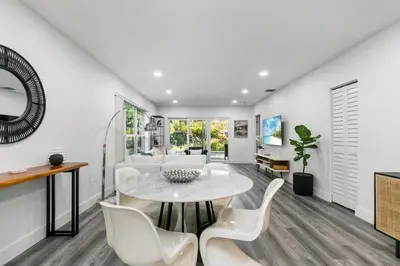 a living room with a table and white chairs at Modern Miami Oasis with Pool & Water View in North Miami